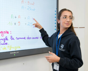 Jeune fille sur un tableau numérique pour une cours de mathématiques